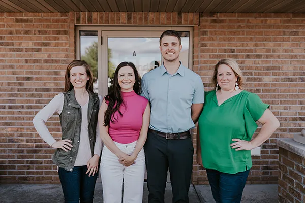 Chiropractors Kallie Madison And Cory Madison With Team In Front Of Building